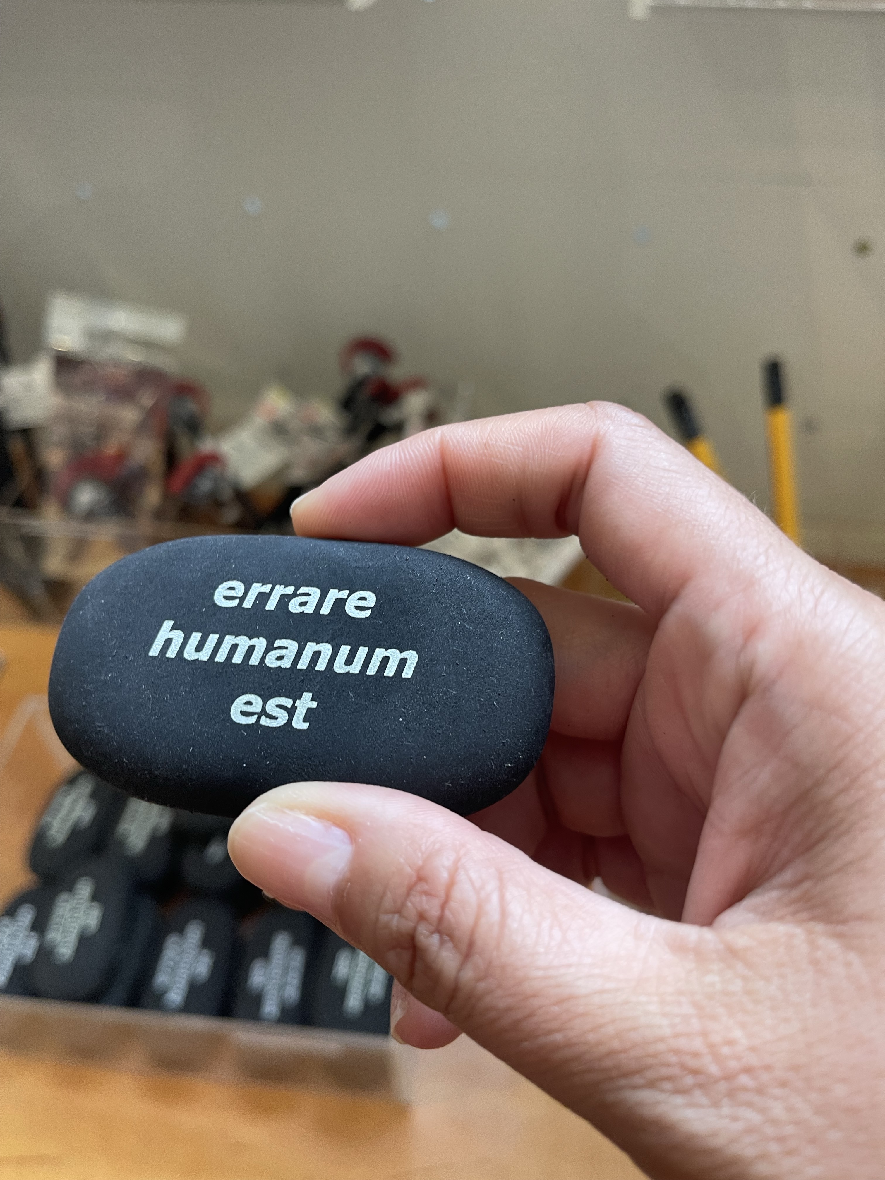 a black eraser with white font that reads errare humanum est